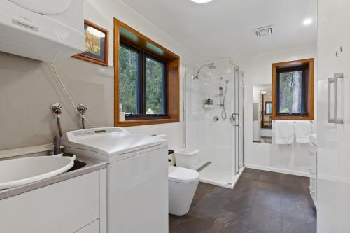 ein weißes Bad mit einem Waschbecken und einem WC in der Unterkunft Hastings Bay Retreat in Hastings