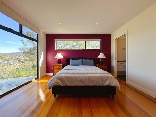 a bedroom with a large bed and a large window at Mountains and Treetops Retreat - Nature Getaway in Lenah Valley