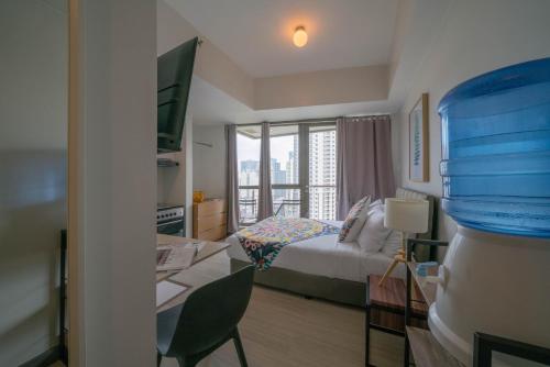 a bedroom with a bed and a desk with a window at KL Tower Makati Apartments by PH Staycation in Manila