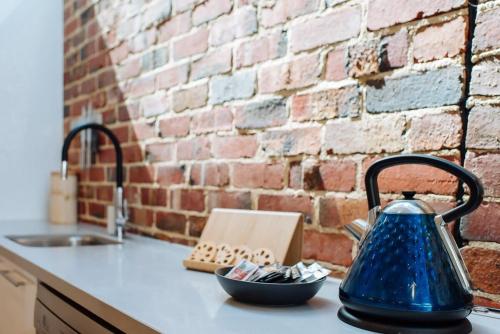 a blue kettle on a kitchen counter next to a brick wall at SENSATIONAL Renovated Cottage in Beautiful Seddon in Seddon
