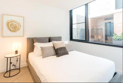 een slaapkamer met een wit bed en een raam bij Cozy 2 Beds Apartment In Fitzroy For Rest And Work in Melbourne