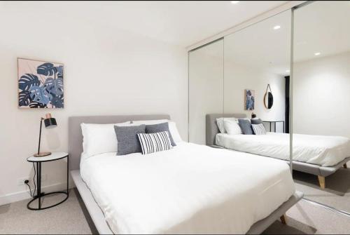 a bedroom with two beds and a mirror at Modern Apartment In Flawless Fitzroy+Carpark in Melbourne