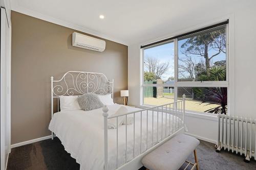 1 dormitorio con cama blanca y ventana grande en The Dolphin Cottage - 250m to bay beach, en Rye
