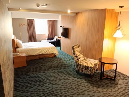 a hotel room with a bed and a chair at Yiting Hotel in Kaohsiung