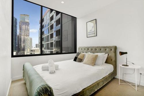 a bedroom with a bed with a large window at Central 15th floor Apt near Flagstaff & QV Market in Melbourne