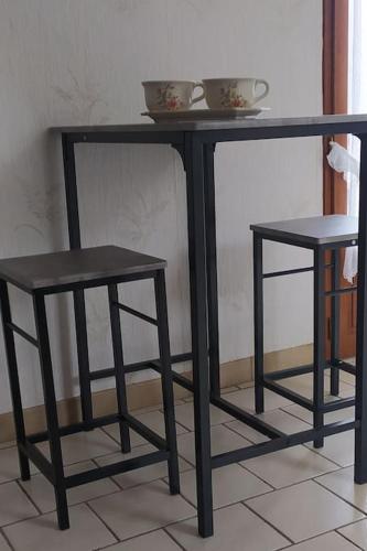 a black table and two stools on a floor at Chambre lit double, Salon, cuisine, jardin in Couze-et-Saint-Front