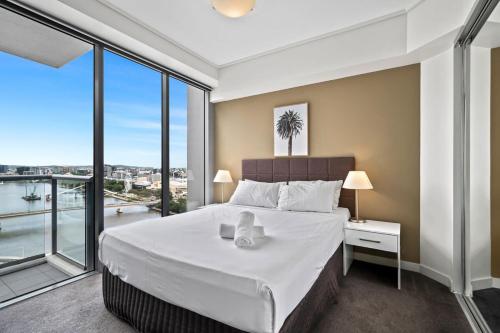 a bedroom with a large bed and large windows at City Living - Brisbane River-View 2 bedroom Apt in Brisbane