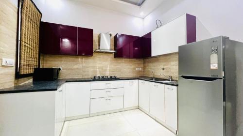 a kitchen with white cabinets and a stainless steel refrigerator at BluO Modern 1BHK - DLF Galleria in Gurgaon