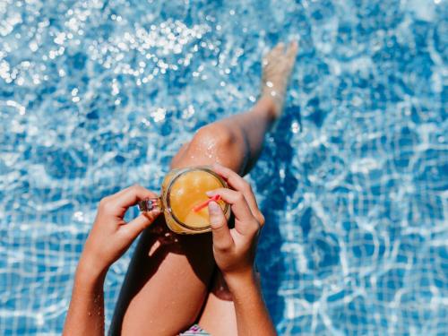 a woman holding a drink in front of a swimming pool at VACATION MARBELLA I Villa Sirio, Golf-Front Villa, Private Pool, Privacy in Marbella