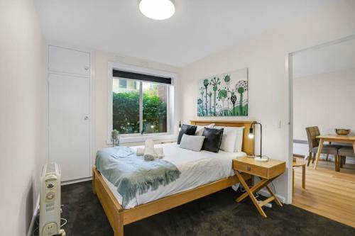 a bedroom with a bed and a desk and a window at Homey 1 bdrm Thornbury Apt near restaurants+shops in Melbourne