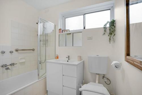 een witte badkamer met een toilet en een douche bij Homey 1 bdrm Thornbury Apt near restaurants+shops in Melbourne