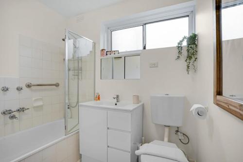 a white bathroom with a toilet and a shower at Homey 1 bdrm Thornbury Apt near restaurants+shops in Melbourne