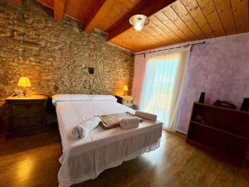 1 dormitorio con cama y pared de piedra en La casa de Claverol, en Claverol