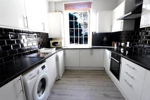 a kitchen with white cabinets and a washer and dryer at 3 Bedroom Prime Angel Location in London