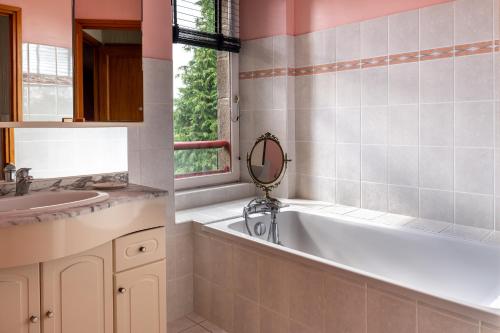 a bathroom with a bath tub and a sink at Gite La Renardière in Langoëlan