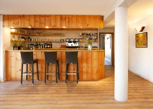 a kitchen with wooden cabinets and bar stools at Hotel Atlantide in Biscarrosse