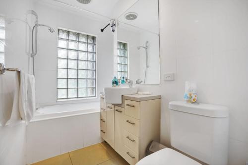 a white bathroom with a tub and a sink at Elwood Elegance by the Beach in Melbourne