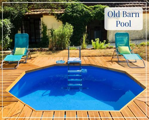 une ancienne piscine de grange avec deux chaises et des chaises autour dans l'établissement PRIVATE POOL with Stunning Views of the Chateau!! Old Barn, à Rouffignac-Saint-Cernin-de-Reilhac