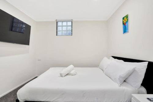 a white bedroom with a white bed and a window at Gem in heart of Melbourne CBD in Melbourne