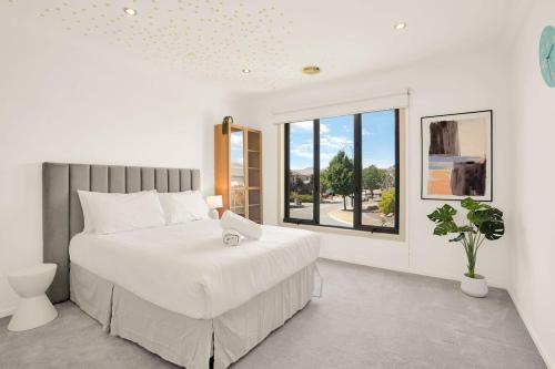 a white bedroom with a large bed and a window at Deluxe Family Montpellier Gardens Estate - Burwood in Burwood