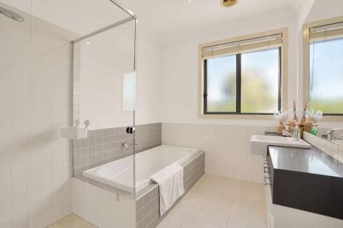 a white bathroom with a tub and a sink at Deluxe Family Montpellier Gardens Estate - Burwood in Burwood