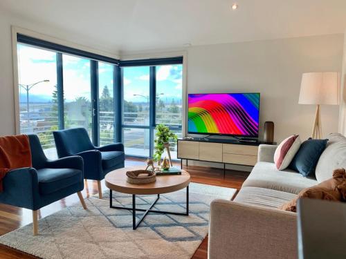 a living room with a couch and a tv at Amazing Beachfront & City Views 2 bed 2 bathroom in Melbourne