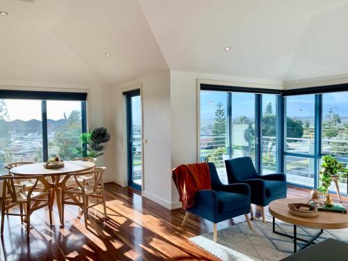 a living room with a table and chairs and windows at Amazing Beachfront & City Views 2 bed 2 bathroom in Melbourne
