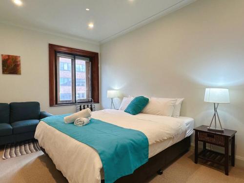 a bedroom with a large bed and a blue chair at Heritage Building Penthouse CBD Apartment in Hobart