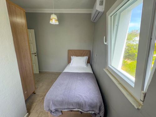 Cama pequeña en habitación pequeña con ventana en Gümüşlük apart, en Bodrum City