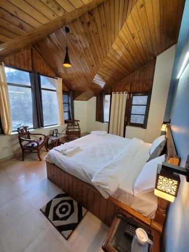 a bedroom with a large bed in a room with windows at Oski Inn in Manāli