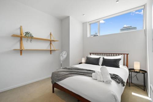 a white bedroom with a bed and a window at A River-side 2bdm Footscray Oasis + Parking in Melbourne
