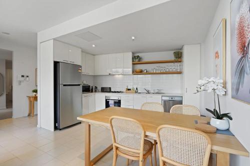 a kitchen with a wooden table and chairs at A River-side 2bdm Footscray Oasis + Parking in Melbourne