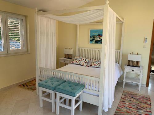 a bedroom with a white canopy bed with two chairs at Charming Seaside House next to Beach in Orebić