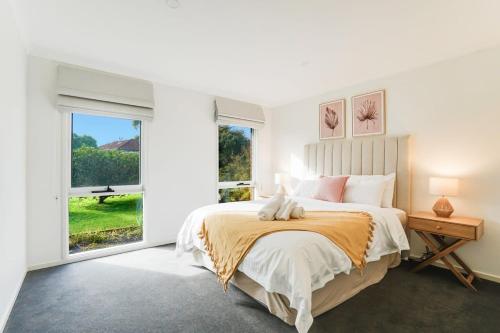 a white bedroom with a large bed and a window at Relaxed at Rosebud-Cosy 3 bedroom beach escape* in Rosebud