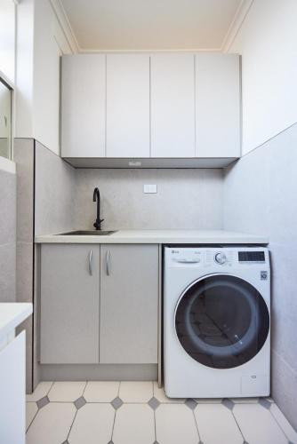 a white kitchen with a washing machine and a sink at Central Classic Collingwood Modern Apt in Melbourne