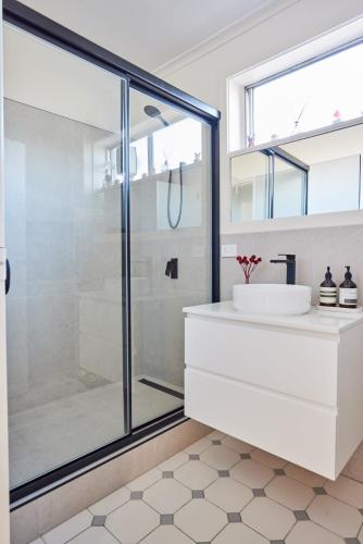 a bathroom with a glass shower and a sink at Central Classic Collingwood Modern Apt in Melbourne
