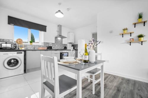 a white kitchen with a table and white chairs at Brand New One Bed Cradley Heath - 4MH - Parking - Netflix - Top Rated in Old Hill