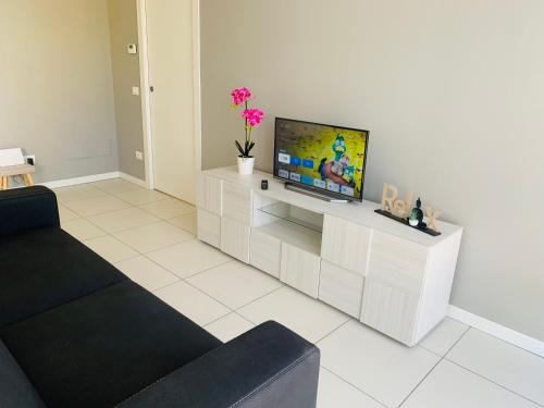 a living room with a tv on a white cabinet at Deny & Carol's house in Somma Lombardo