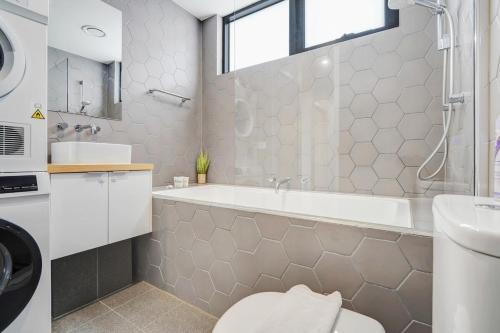 a bathroom with a tub and a toilet and a sink at Contemporary Central Brunswick 2-Story Townhouse* in Melbourne