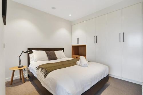 a bedroom with a large bed with white cabinets at Richmond Heritage Executive Apt for 2 w parking in Melbourne