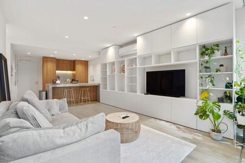 a living room with a couch and a tv at Stylish Gem @ St kilda Rd Next to Grand Prix in Melbourne