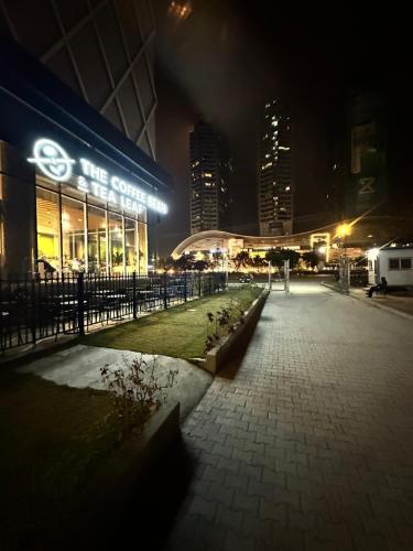 a city at night with a bike store at Designer's Luxe Delight-Elysium Tower in Islamabad