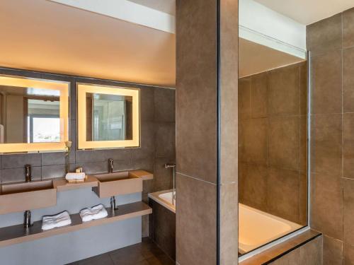 a bathroom with two sinks and a shower at Novotel Abidjan in Abidjan