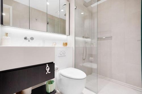 a white bathroom with a toilet and a shower at Cozy Nest in Prime Hawthorn w parking & pool in Melbourne