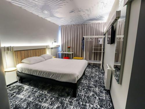 una camera con letto in una stanza con soffitto di ibis Haguenau Strasbourg Nord a Haguenau