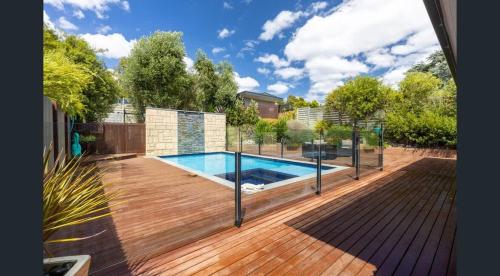 a backyard with a swimming pool and a wooden deck at The Great Entertainer in Rye w pool near the beach! in Rye