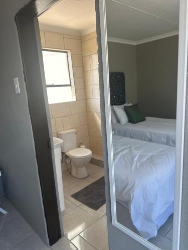 a mirror in a room with a bed and a toilet at Maphuthi River Lodge in Ga-Manapane