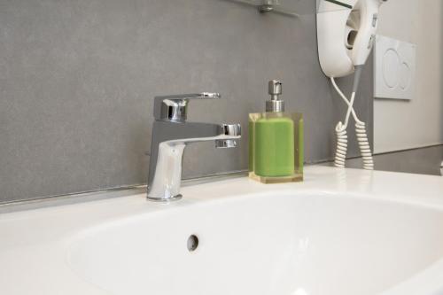 a sink with a faucet and a green soap dispenser at Le Tre Sorelle in Bari