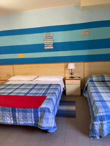 two beds in a room with blue and white stripes at Hotel Lupo di mare in Marina di Castagneto Carducci