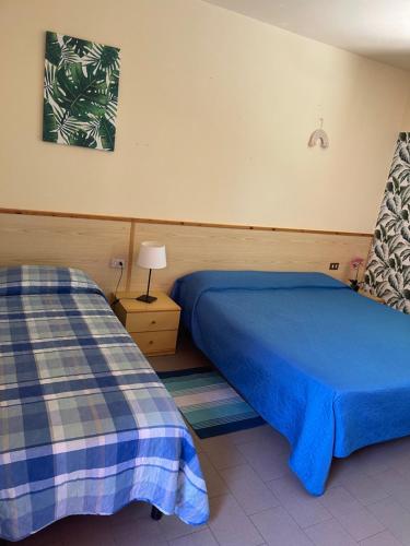 マリーナ・ディ・カスタニェート・カルドゥッチにあるHotel Lupo di mareのベッドルーム1室(ベッド2台、テーブルの上にランプ付)